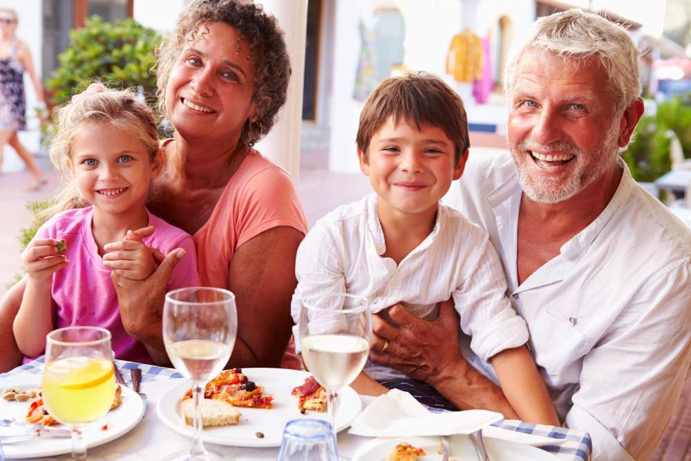 Understanding, Treating and Travelling with Eczema: Happy grandparents on holiday with kids eating dinner