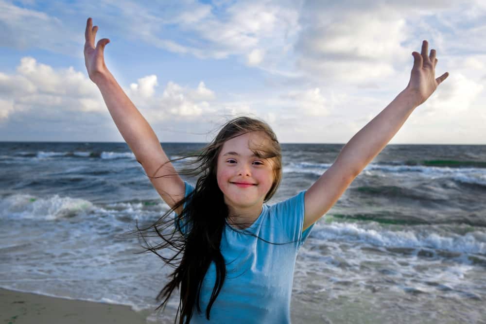 10 tips for Travelling with Someone who needs Full Time Care: Young girl with down syndrome enjoying the beach