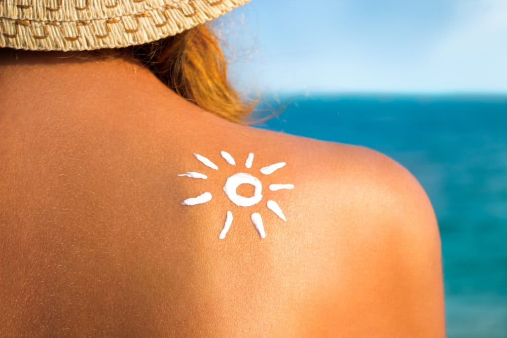 Preparing for a holiday when you have a medical condition: young woman with sun cream on her shoulder